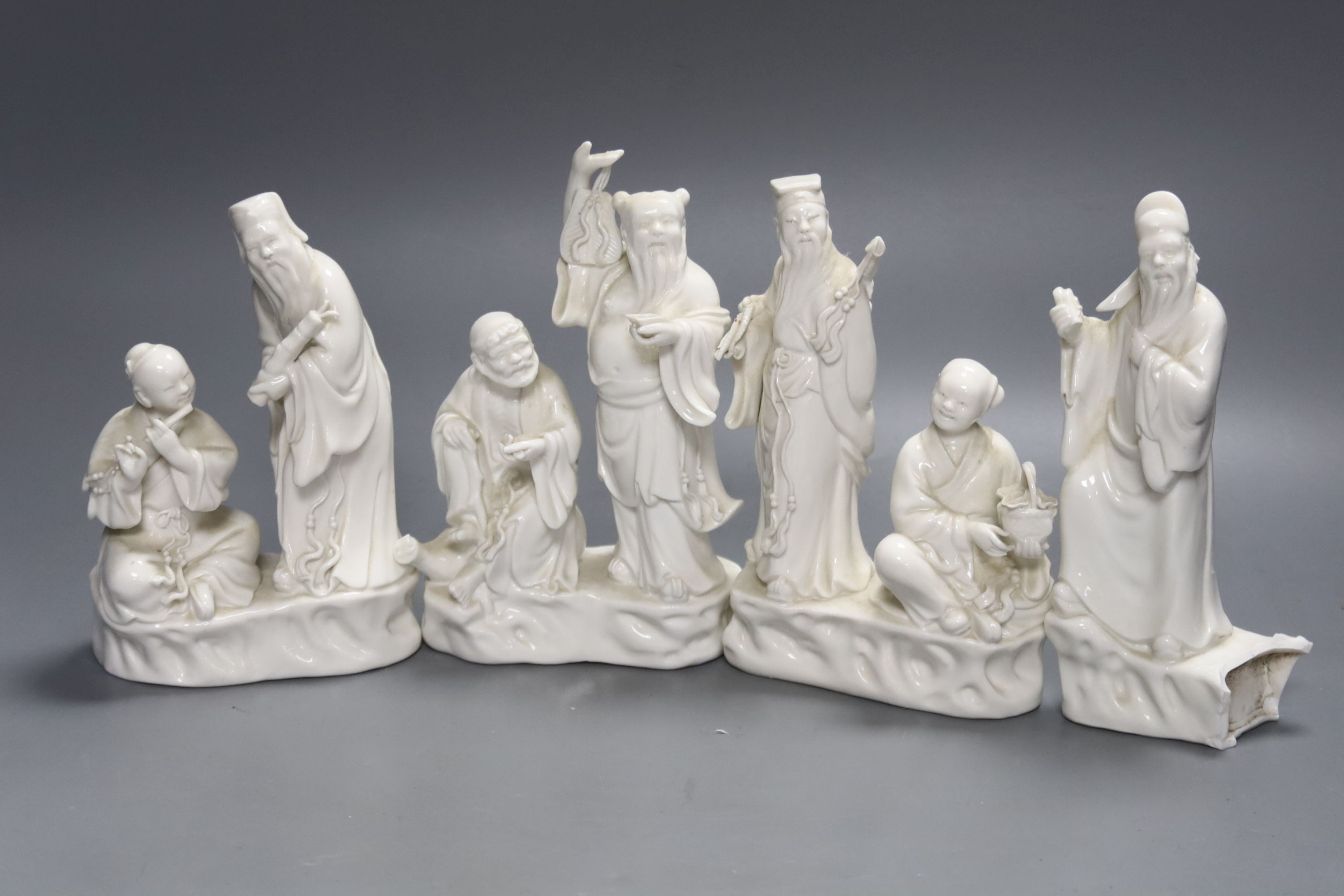 Three Chinese white porcelain groups of deities and a fragment, tallest 16cm